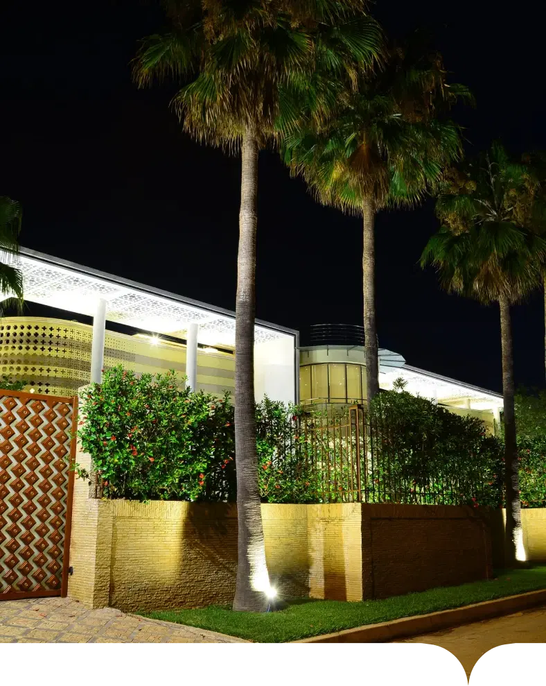 The street front of Oumnia Palace at night, with its palms and screen wall