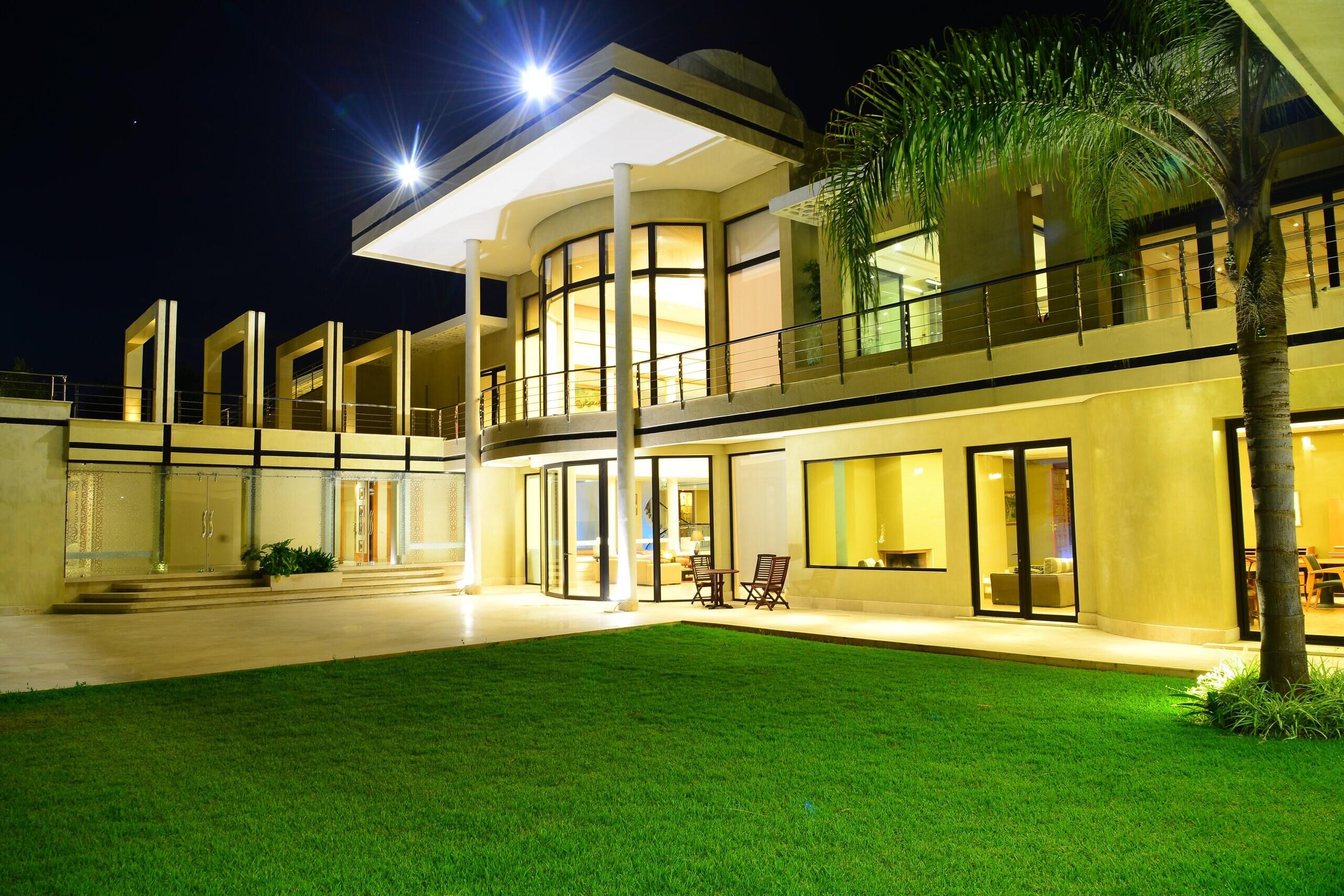 The garden façade lit at night above the lawn