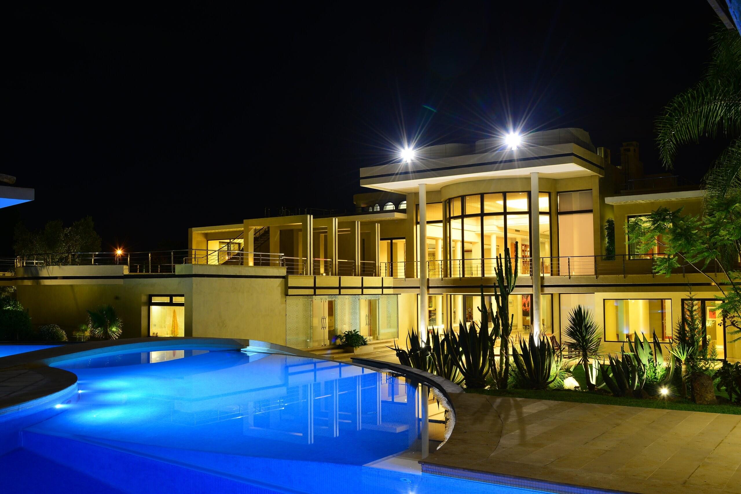 The pool lit blue at night in front of the garden façade