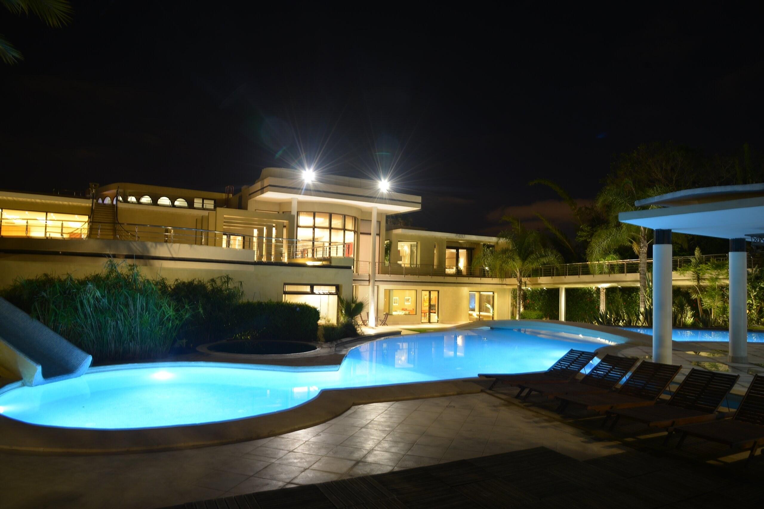 The pool at night, with the slide and the house lit beyond
